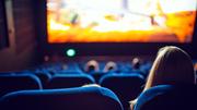 Moviegoers seated in a cinema watching a film on a large theatre screen.